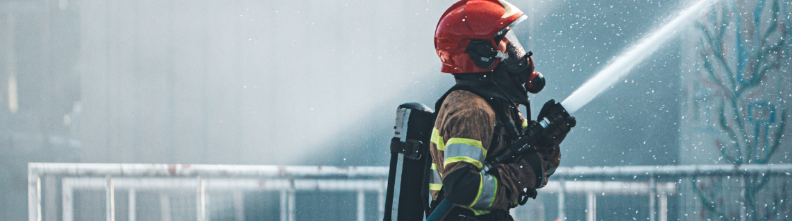 Decorative image showing a firefighter holding a running fire hose